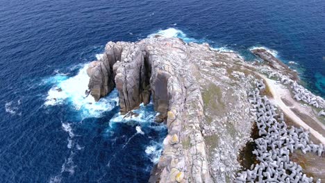 Aerial-drone-rotating-shot-of-extreme-waves-splashing-on-the-rugged-paper-cliffs-in-Morás,-Xove,-Lugo,-Galicia,-Spain-at-daytime