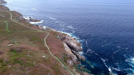 Aerial-bird's-eye-view-over-an-area-called-paper-cliffs,-in-the-area-of-Morás,-Xove,-Lugo,-Galicia,-Spain-with-view-of-narrow-pathway-along-the-shoreline-at-daytime