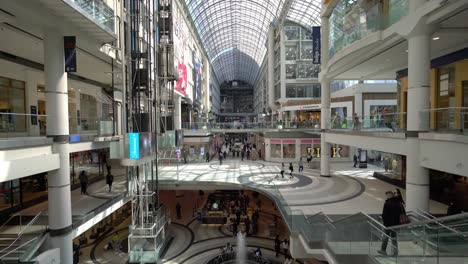 Modern-mall-shopping-under-the-glass-roof-of-the-Toronto-Eaton-Centre-illuminating,-wide-angle