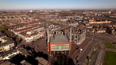 Absteigende-Luftaufnahme-Eines-Farbenfrohen-Gebäudes-Mit-Moderner-Moscheearchitektur-Im-Multikulturellen-Wohnviertel-Lombok-Im-Hellen-Sonnenaufgangslicht-Am-Frühen-Morgen-Mit-Zwei-Türmen-Vor-Klarem-Blauen-Himmel