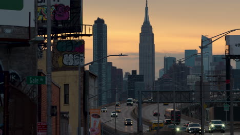 Empire-State-Building-Und-Verkehr-Auf-Der-Autobahn,-Gesehen-Von-Queens,-New-York,-Bei-Sonnenuntergang