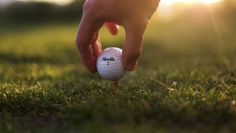 Die-Hand-Des-Golfspielers-Legt-Auf-Der-Driving-Range-Einen-Maßgeschneiderten-Nudelgolfball-Auf-Den-Abschlag
