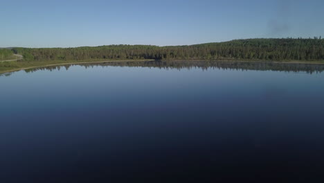 Luftaufnahme-über-Einem-Blauen,-Noch-Bewässerten-See-Mit-Blick-Auf-Einen-Wunderschönen-üppigen-Grünen-Wald-Im-Norden-Von-Ontario,-Kanada
