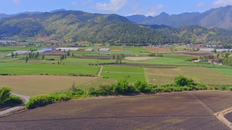 Aerial-forward-view-of-Constanza-cultivated-fields-and-landscape-with-mountains-in-background,-Dominican-Republic