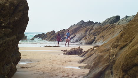 Englische-Ethnische-Mutter-Und-Vater-Tragen-Kleinkind-Und-Gehen-Auf-Strandsand-In-Einer-Geschützten-Bucht-In-Cornwall,-England-–-Statische-Ansicht