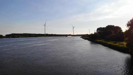 Aerial-Dolly-Over-Oude-Maas-With-Somtrans-X-Inland-Tanker-Travelling-Along-Oude-Maas-With-Row-Of-Wind-Turbines-In-background