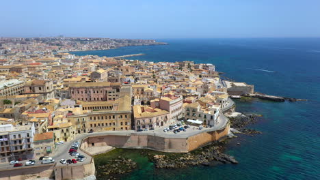 Revealing-drone-shot-of-Syracuse-coastline-revealing-the-Ionian-Sea,-historic-city-on-the-Italian-island-of-Sicily