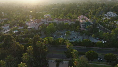 Drone-Shot-Approaching-Beverly-Hills-Hotel-at-Sunset,-Iconic-and-Historic-Luxury-Resort-in-California-in-Warm-Sun