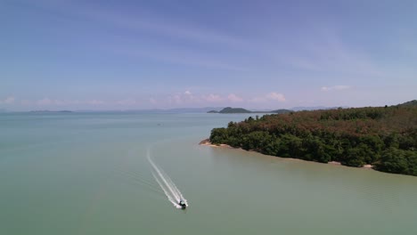Luftaufnahme-Der-Kokosnussinsel-In-Thailand,-Während-Ein-Lokales-Longtail-Boot-Im-Türkisblauen-Tropisch-blauen-Wasser-Vorbeifährt