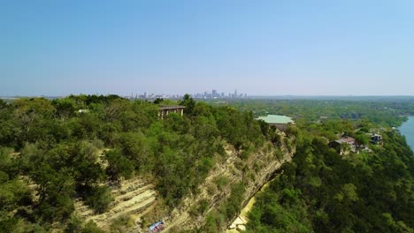Drone-footage-panning-quickly-left-to-right-at-Covert-Park-at-Mount-Bonnell-with-the-city-of-Austin,-Texas-in-the-background