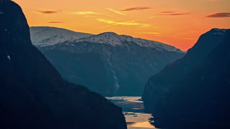 Eine-Ruhige-Szene-Mit-Atemberaubendem-Sonnenuntergang-Mit-Bergen-Und-Einem-Fluss,-Der-Durch-Ein-Tal-Fließt