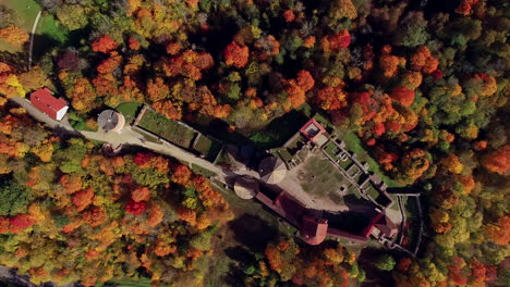 Aerial-drone-bird's-eye-view-of-Turaida-Castle-in-Byrdeye,-Latvia-surrounded-by-colorful-autumnal-forest-on-a-bright-sunny-day