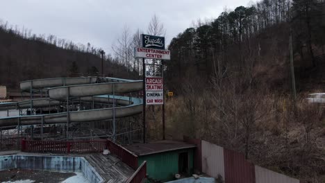 Drone-Footage-Rising-in-Front-of-the-Fugates-Entertainment-Center-Sign-in-Eastern-Kentucky-with-the-Abandoned-Waterslides-Sitting-in-the-Background