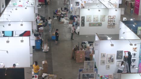 View-from-above-of-art-exhibitors-preparing-ahead-for-the-opening-of-a-contemporary-art-fair-as-they-setup-and-decorate-the-booths-and-hang-the-painting-for-sale-during-the-installation-day