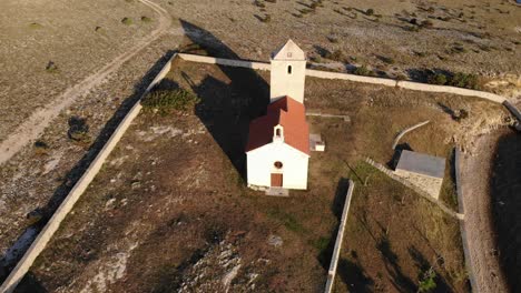 Hermosa-Iglesia-Tradicional-De-Una-Pequeña-Isla-En-El-Adriático,-Vista-Aérea-Acercándose-Desde-Arriba