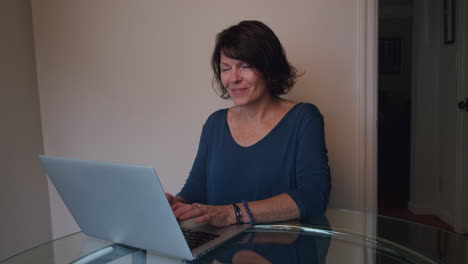 Woman-at-home-on-laptop-computer-typing-with-happy-facial-expression