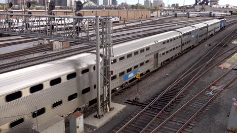Una-Locomotora-Tirando-De-Vagones-De-Tren-De-Pasajeros-A-Través-Del-Patio-Ferroviario-4k