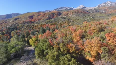 A-drone-flies-over-the-rocks-and-slopes-of-Dry-Creek-Trailhead-in-Alpine,-Utah-as-leaves-change-into-brilliant-fall-colors
