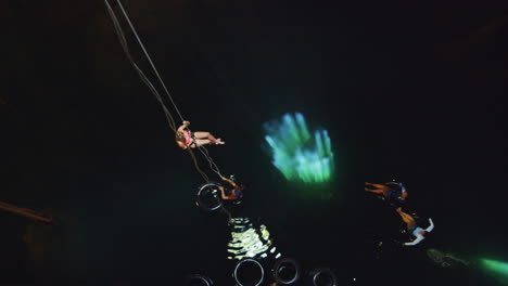 Slow-motion-shot-of-blonde-girl-lowering-to-the-cenote-with-the-rope-in-Cancùn,-Mexico