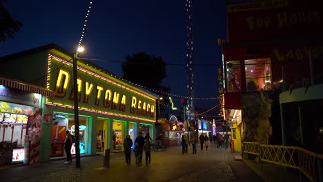 Belebte-Geschäftsstraße-Mit-Einem-Beliebten-Warenladen-Und-Menschen,-Die-Nachts-Im-Wiener-Prater-Spazieren-Gehen-–-Stabile-Aufnahme