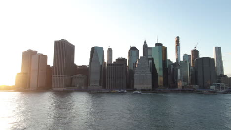 Wide-angle-aerial-tracking-shot-of-Lower-Manhattan,-New-York-City-at-dusk-on-a-clear-summer-evening