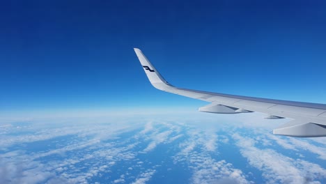 Airplane-Wing-in-the-air,-White-Clouds-and-beautiful-Blue-Sky