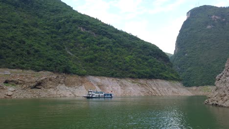 Small-tourist-boat-sailing-on-the-Shennong-Xi-Stream,-estuary-of-the-mighty-Yangtze-river,-Hubei-Province,-China