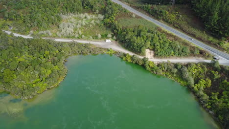 Aerial-drone-shot-of-a-steaming-lake-with-road-and-RV-in-the-Rainforest