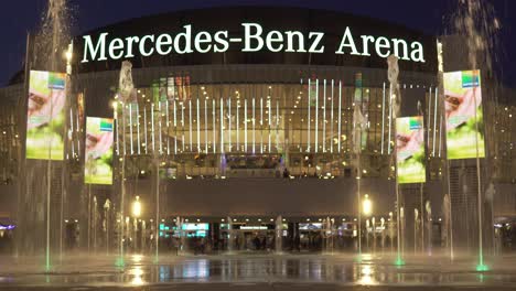 Moderner-Mercedes-Benz-Platz-In-Berlin-Bei-Nacht-Mit-Unterhaltungsarena-Und-Springbrunnen-Davor