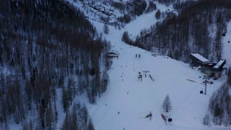 Wunderschöne-Luftaufnahme-Eines-Belebten-Skigebiets-Im-Winter-Mit-Skifahrern,-Die-Den-Berg-Hinunterfahren,-Und-Seilbahnen-Auf-Skiliften