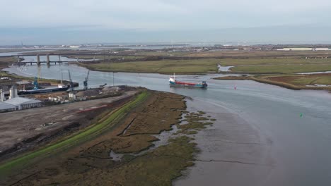 Amplia-Vista-Aérea-Del-Muelle-De-Ridham-En-Kemsley,-Reino-Unido-Con-Un-Barco-Navegando-A-Lo-Largo-De-La-Ciénaga