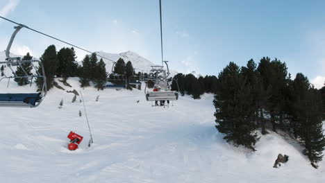 People-sitting,-riding-pov-on-snowy-winter-landscape-ski-lift-up-to-mountain-peaks,-Austria