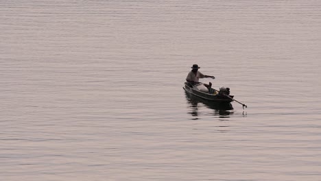 Pescador-Perfilando-Mientras-Lanza-Y-Saca-Su-Red-En-El-Río-Antes-Del-Anochecer,-En-Cámara-Lenta