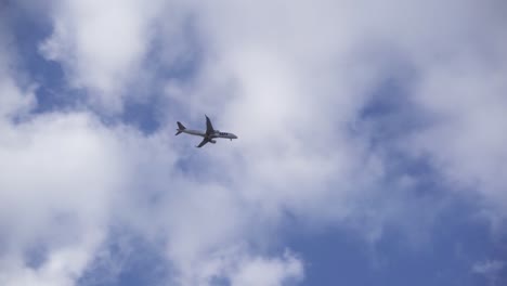 LOT-Polish-Airlines-plane-against-blue-sky-with-few-clouds,-low-angle-zoom-view