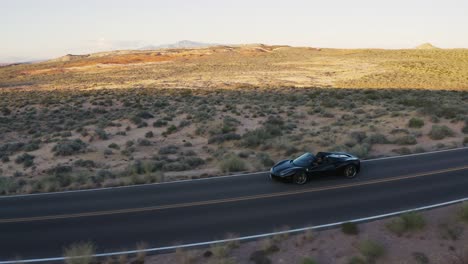 Schwarzer-Ferrari-Fährt-Auf-Offener-Straße-Im-Valley-Of-Fire,-Nevada,-Bei-Sonnenuntergang