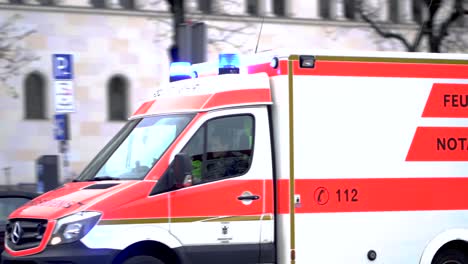 Slow-motion-of-german-ambulance-driving-down-the-road-with-sirens