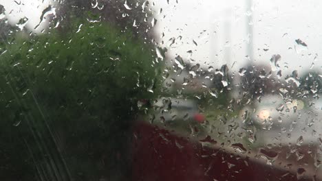 Rain-Falling-On-Window-With-Blurred-Background-Of-Traffic-Going-By