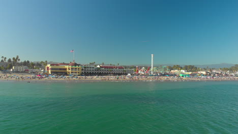 Low-Aerial-Slide-Over-Water-of-Amusement-Park-on-Beach