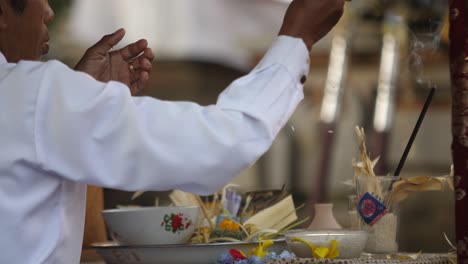Close-up-view-of-Hindu-priest-performing-ceremony-and-tossing-rice-offering-from-altar-at-temple
