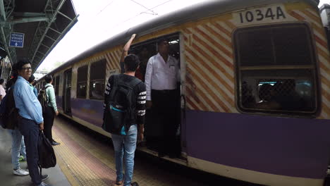 Train-arriving-at-Mumbai-station,-people-wait-on-platform-while-it-stops