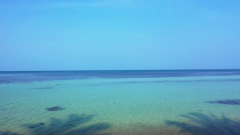 Peaceful-seascape-with-clear-blue-sky-over-calm-lagoon-with-algae-pattern-on-sea-bottom-in-Malaysia,-copy-space