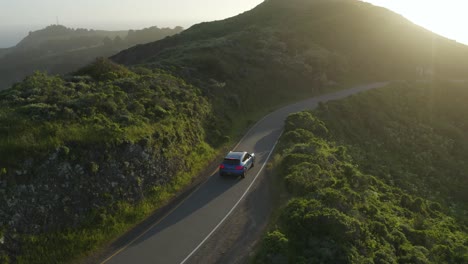 Blue-Porsche-Macan-travelling-through-the-Marin-Headlands-in-San-Fransisco,-California,-at-sunset