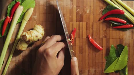 Carefully-slicing-red-spicy-chili-peppers-on-a-bamboo-cutting-board-with-a-chef-knife---Top-view