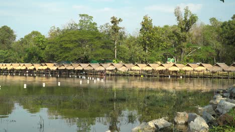 Beautiful-Huay-Tung-Tao-Lake-in-Chiang-Mai,-lush-forest-backdrop,-displaying-the-straw-huts-on-the-lakefront