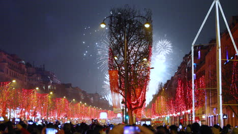 Paris-celebration-of-on-main-Champs-Elysees-captured-fireworks-during-the-arrival-of-surrounded-by-crowd-of-people-on-the-main-street-with-a-view-Triumphal-Arch-a-red-covered-street