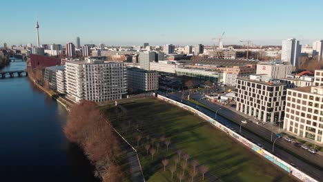 Berliner-Mauer-Von-Der-Spree-Mit-Einer-Drohne,-Die-Entlang-Des-Flusses-Fliegt-Und-Die-Berliner-Fernsehantenne-In-4k-24fps-Zeigt