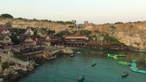 Anchor-Bay,-Vuelo-Sobre-El-Parque-Inflable-Del-Mar-Acercándose-A-Las-Coloridas-Casas-En-El-Antiguo-Plató-De-Cine-Del-Pueblo-De-Popeye