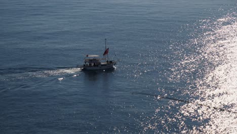 Halbnahe-Aufnahme,-Boot-Segelt-über-Das-Meer,-Im-Vordergrund-Spiegelt-Sich-Die-Sonne-Auf-Dem-Meeresfischer