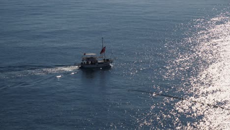 Medium-shot,-boat-sailing-the-sea,-sun-reflecting-on-the-sea-fisherman-in-the-foreground