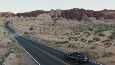 Schwarzes-Ferrari-Cabrio,-Das-Im-Tal-Des-Feuers,-Nevada,-Bei-Sonnenuntergang-In-Den-Rahmen-Fährt